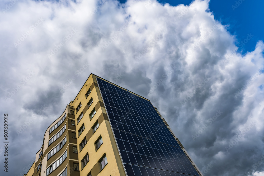 solar panels on the wall of a multi-storey building on storm clouds background. Renewable solar energy. an energy-efficient home that uses the energy of the earth, sun, air and wastewater