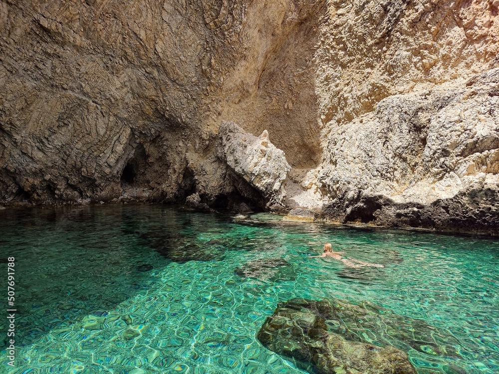 Young blonde woman swimming between the rocks on summer vacations on Greece island Rhodes Young blonde woman swimming between the rocks on summer vacations on Greece island Rhodes