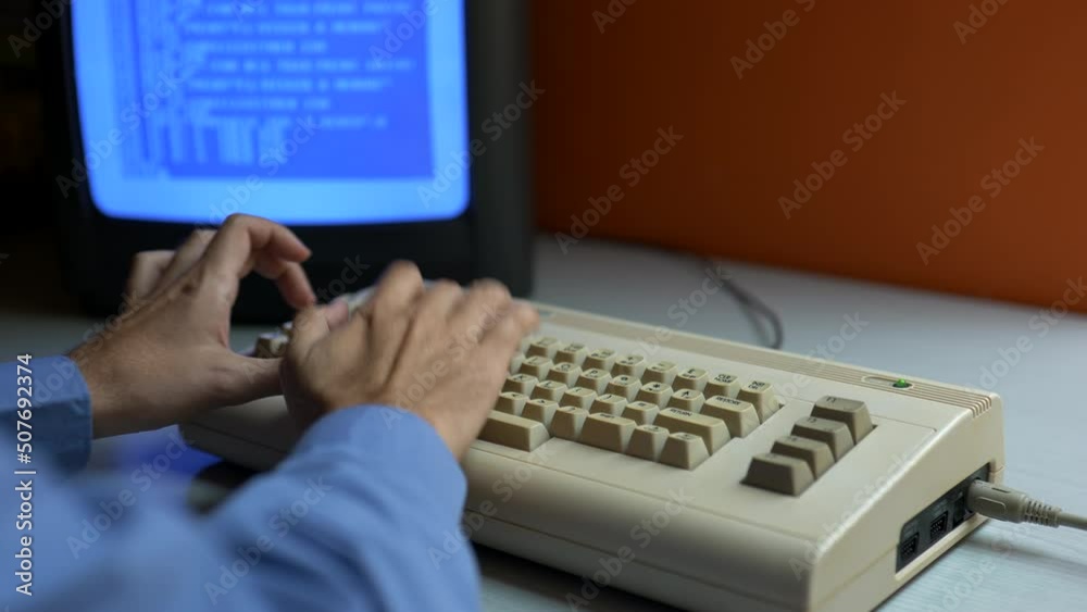 Man in a blue shirt is programming on an old computer