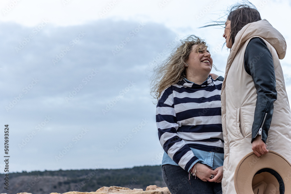 A lesbian couple outdoors on a windy day hanging out in nature