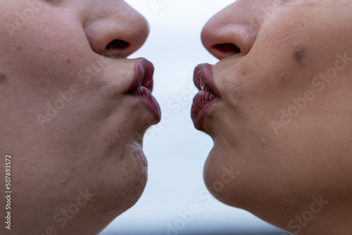фотографія Close up of two women puckering lips about to kiss.