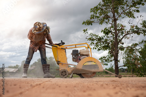 Construction worker using road cutting machinery to cut road surface, Thailand photo