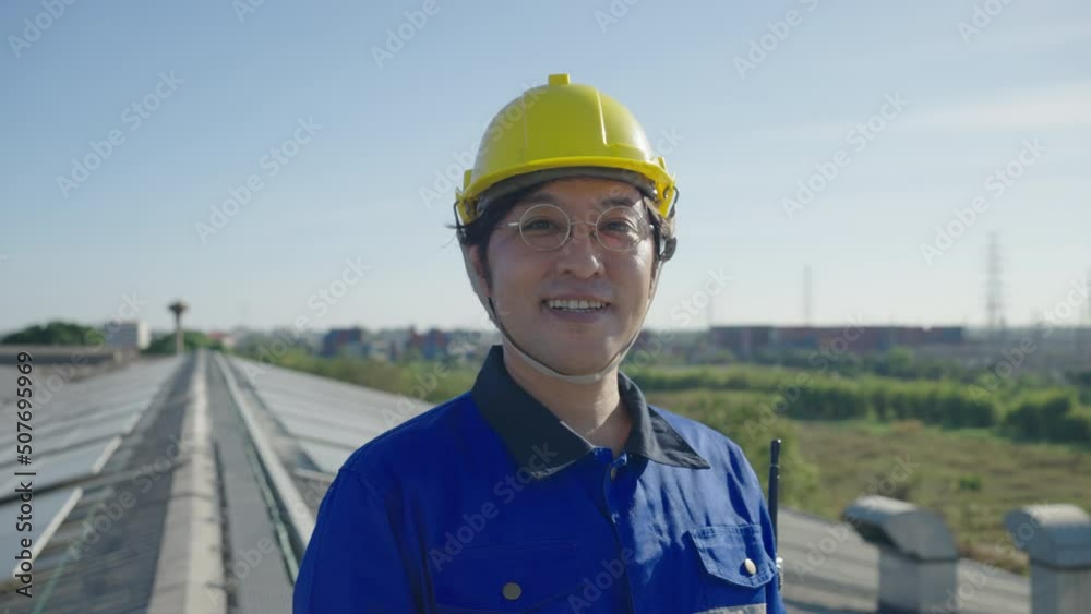 Portrait of Asian engineer on background field of photovoltaic solar panels solar cells on roof top factory. Portrait of Asian engineer on background field of photovoltaic solar panels solar cells on roof top factory.
