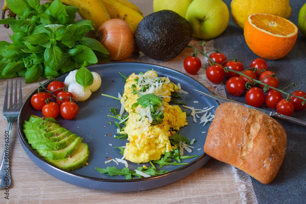French omelette dish. Delicous homemade french omlette filled with cheese. Plating with fresh vegetables like avocado, cherry tomatoes, but also basil and mozzarella. French omelette dish. Delicous homemade french omlette filled with cheese. Plating with fresh vegetables like avocado, cherry tomatoes, but also basil and mozzarella.