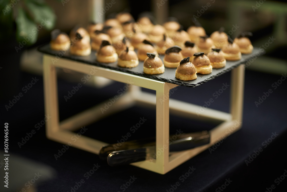 catering. Small portioned snacks on a stand. Sweets, Small sandwiches, canapes
