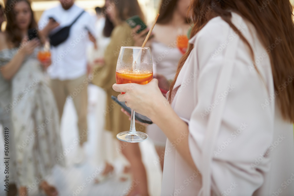 The girl is holding a glass with a cocktail. A party. The girl is holding a glass with a cocktail. A party.