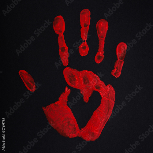 Red palm print on black background with heart, stop bloodshed and war, peace concept. photo