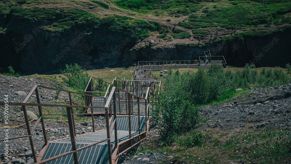 Aerial drone panorama of studlagil canyon in Iceland, picturesque valley with basalt columns standing high on a warm summer day. Closeup of the stairs leading up. Aerial drone panorama of studlagil canyon in Iceland, picturesque valley with basalt columns standing high on a warm summer day. Closeup of the stairs leading up.