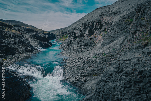 Aerial drone panorama of studlagil canyon in Iceland, picturesque valley with basalt columns standing high on a warm summer day. Closeup of the basalt tiwers in the water
