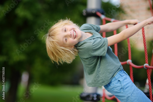 Cute perky preschooler boy having fun on outdoor playground. Spring or summer or autumn active sport leisure for kids. Outdoor activities for family with children.