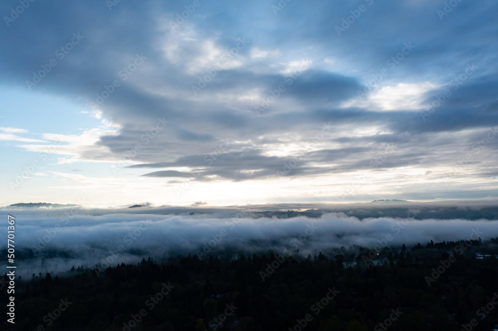 A serene sunrise illuminates low clouds and fog over the Willamette River south of Portland, Oregon. This scenic Pacific Northwest region is known for its moist climate.