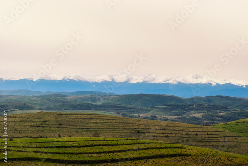 Beautiful landscape view a panoramic view of the Retezat mountains, Carpathians, Romania. View of the snowy peaks behind the colorful fields.