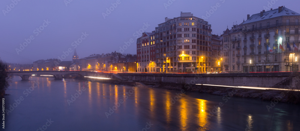 Fototapeta premium View on the night light of buildings near river in Grenoble of France outdoors.