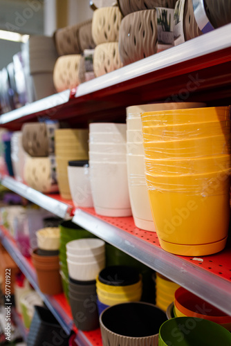 Different plastic flower pots on supermarket shelf. Row of flowerpots in shop or agricultural store.