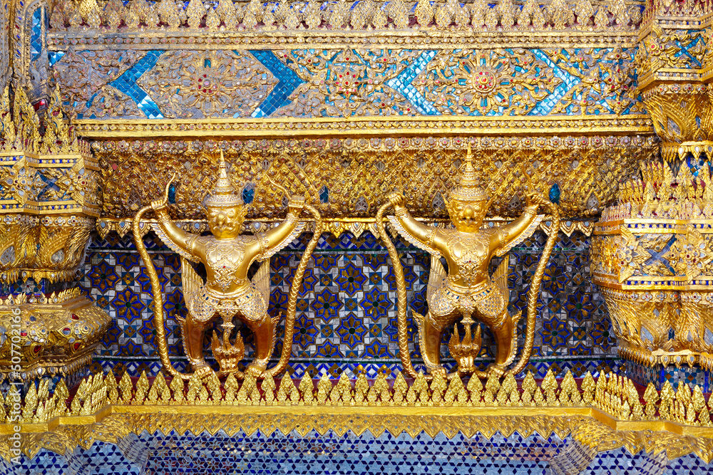 Golden garuda and naga statue, decoration on a wall of The Emerald Buddha temple, Wat Phra Kaew, Grand Palace, Bangkok, Thailand.