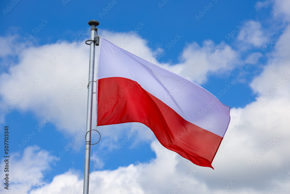 Obraz na płótnie Polska flaga biało-czerwona powiewająca na maszcie na tle błękitnego nieba w salonie