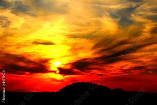 Apocalyptic scenery with strong dark hilly Marche landscape standing out from a bath of violent clouds with raging red and yellow colours amongst the sunset sky