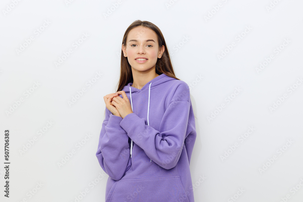 a delightful attractive woman stands on a white background in a purple tracksuit holding her hands joined together against her, smiling happily a delightful attractive woman stands on a white background in a purple tracksuit holding her hands joined together against her, smiling happily