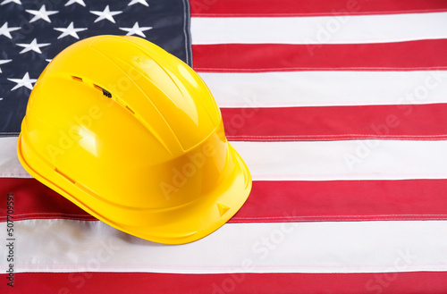 Yellow protective hard hat on American flag. Space for text photo