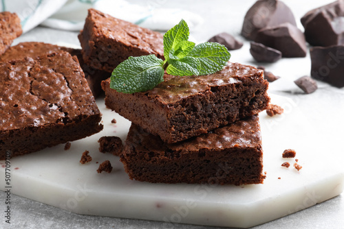 Delicious chocolate brownies with fresh mint on grey table