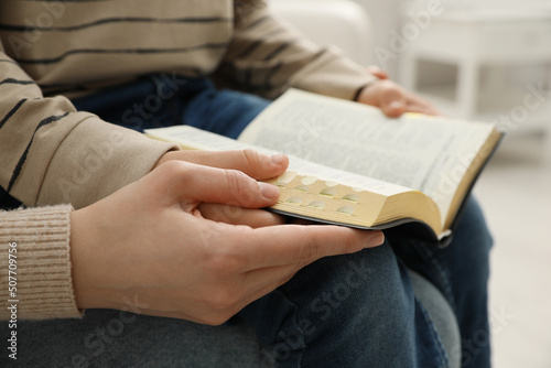 Boy and his godparent reading Bible together indoors, closeup