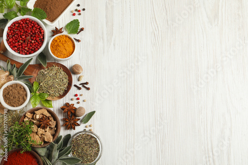 Different fresh herbs and spices on white wooden table, flat lay. Space for text