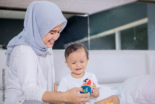 Muslim woman playing with her baby on bed photo