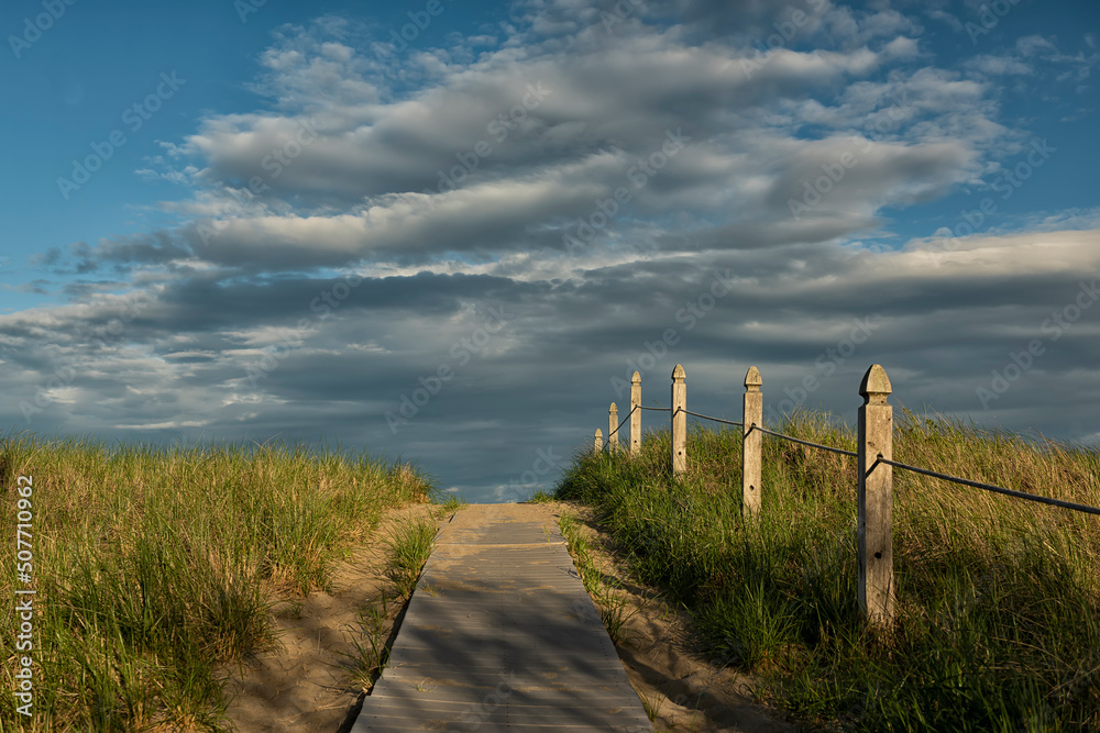 Path to the coast of the ocean from wooden boards. Sandy beach and sky on the ocean. USA. Maine.
