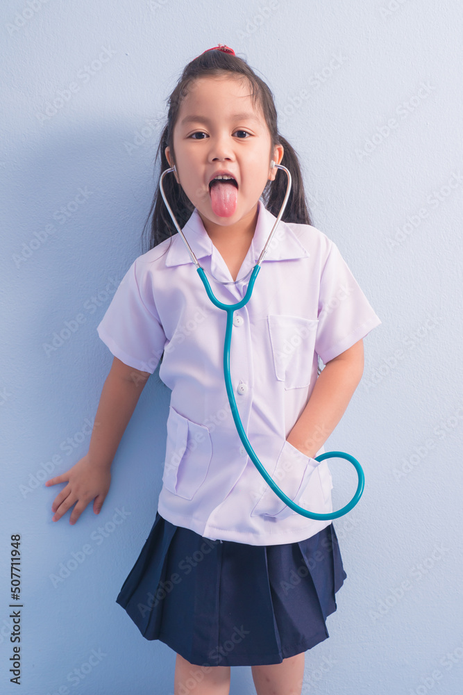 Happy cute girls in white medical uniform and stethoscope act like doctor. child dreams of becoming a doctor career concept Happy cute girls in white medical uniform and stethoscope act like doctor. child dreams of becoming a doctor career concept