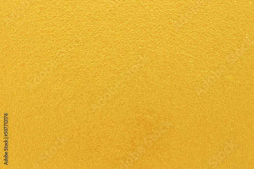Gold or yellow paint on cement wall texture background.
