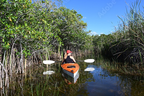 Woman kayaking on Nine Mile Pond in Everglades National Park, Florida on clear sunny April afternoon.
