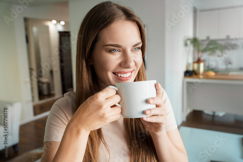 Portrait of joyful young woman smiling enjoy hot drink in cup