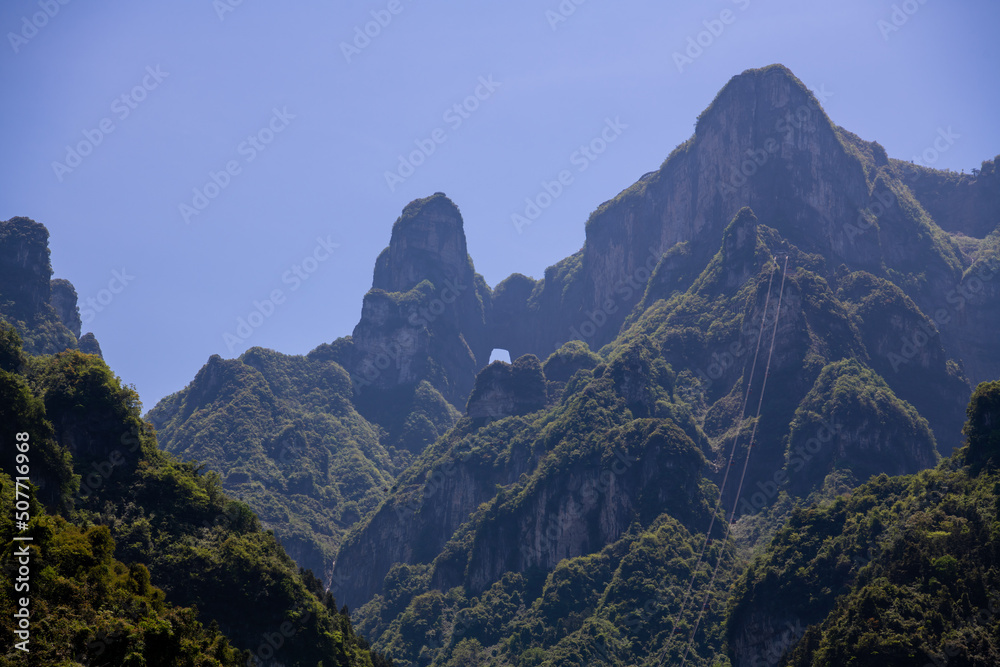 Horizontal image of Tianmen cave from below in Tianmen Nationak park, Zhangjiajie, Hunan, China, copy space for text, blue sky