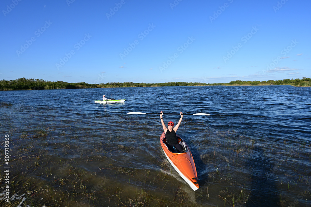 Woman and active senior kayaking on Nine Mile Pond in Everglades National Park on clear sunny April afternoon.
