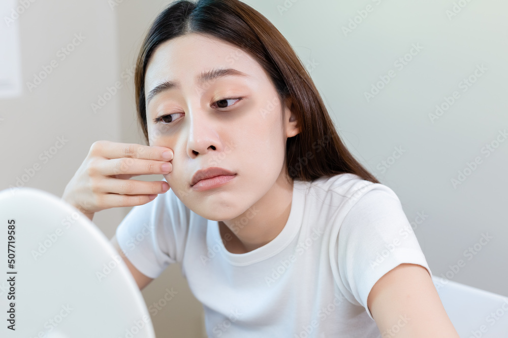 Asian young female stress looking mirror check have dark eye circles on face from staying up sleepy late. from hard work, no time to sleep. Asian young female stress looking mirror check have dark eye circles on face from staying up sleepy late. from hard work, no time to sleep.