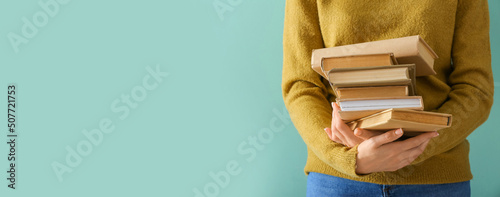 Young woman holding many books on color background with space for text