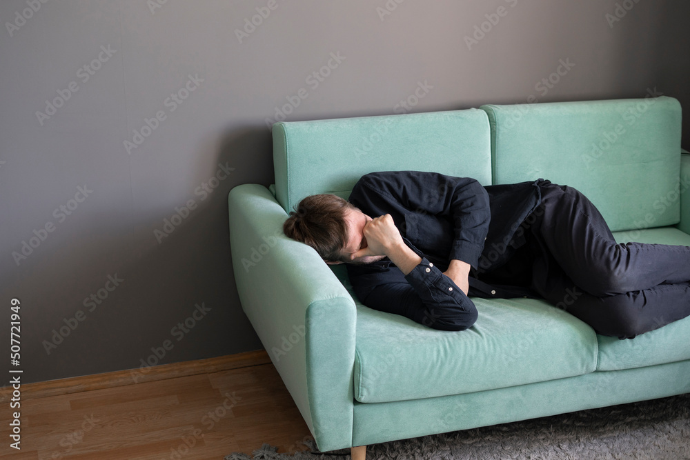 young guy lying and sleeping on the sofa at home in the afternoon