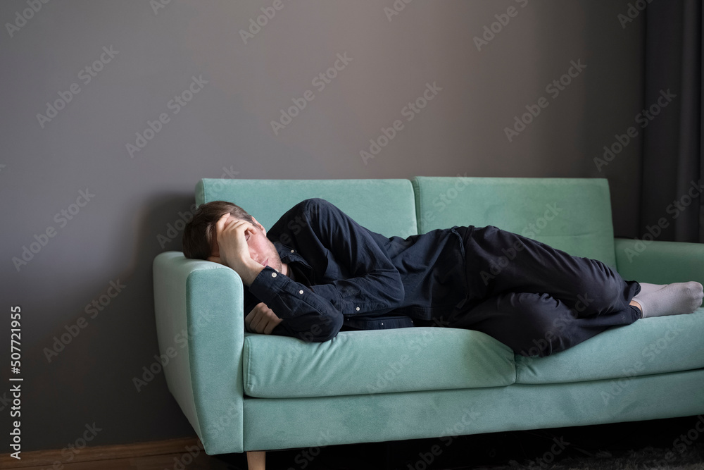 Obraz premium young guy lying and sleeping on the sofa at home in the afternoon