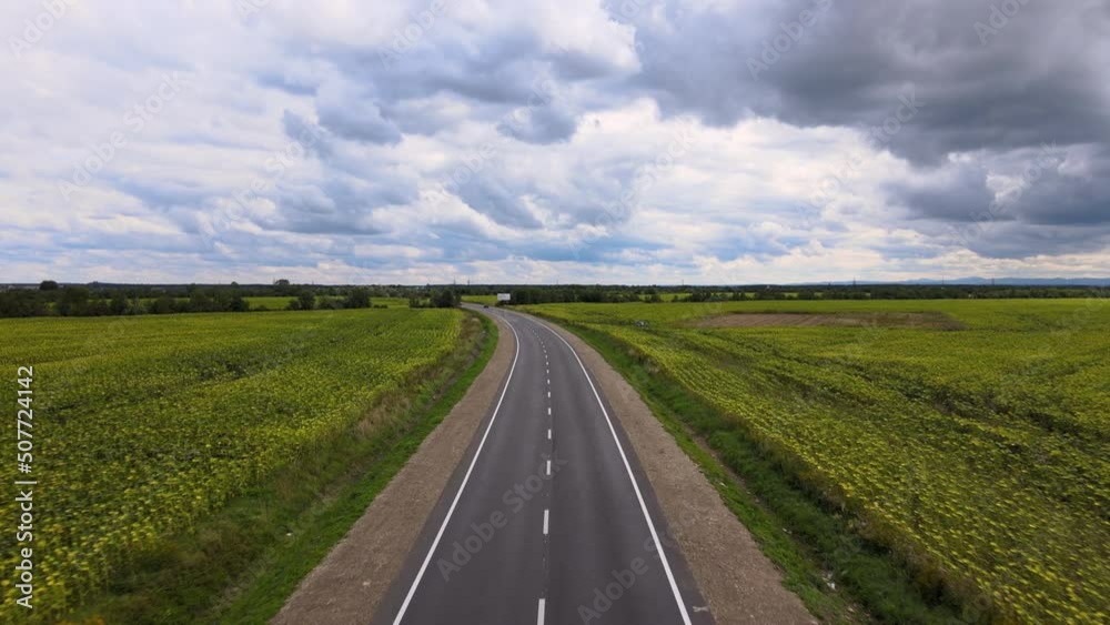 Aerial view of intercity road between green agricultural fields with fast driving cars. Top view from drone of highway traffic