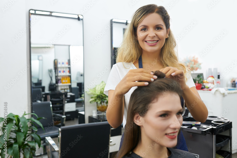 Hairdresser dividing hair of client in sections to applying dye on each one Hairdresser dividing hair of client in sections to applying dye on each one