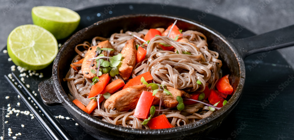 Frying pan with tasty soba noodles and meat on dark background, closeup Frying pan with tasty soba noodles and meat on dark background, closeup