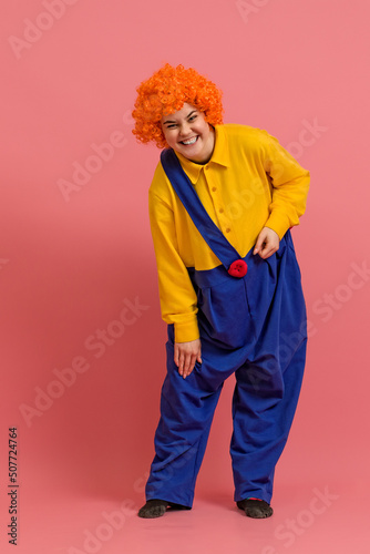 smiling clown in a wig and a yellow-blue suit leaned over on a colored background