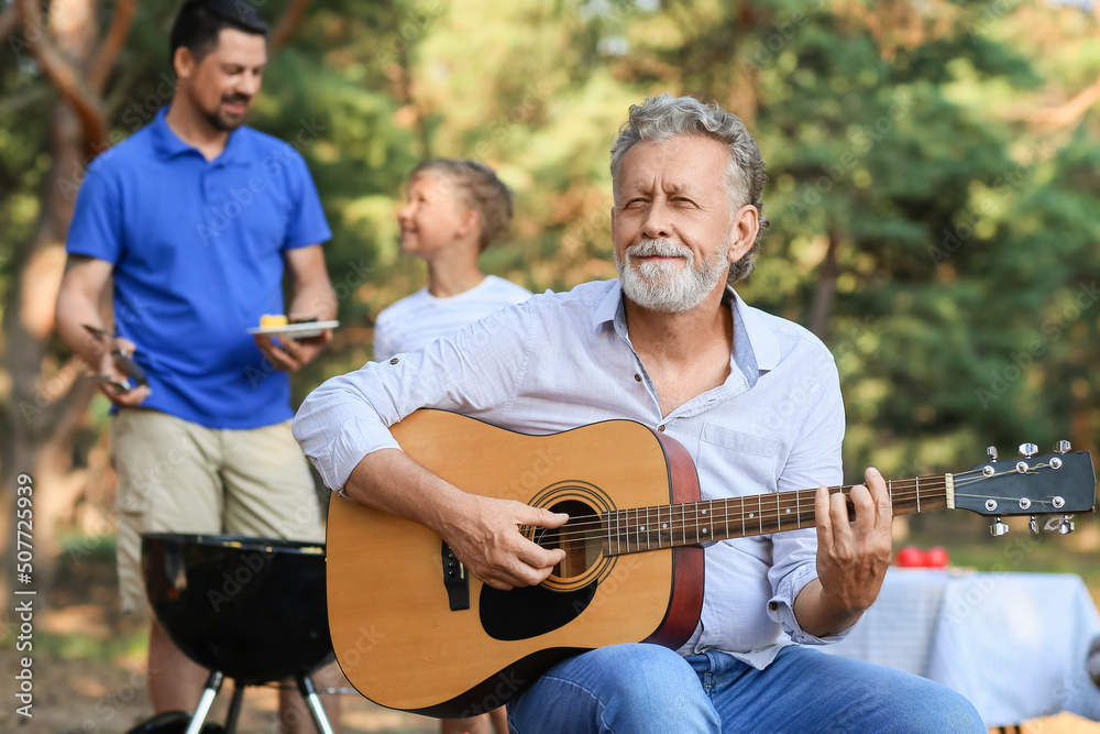 Senior man playing guitar at barbecue party