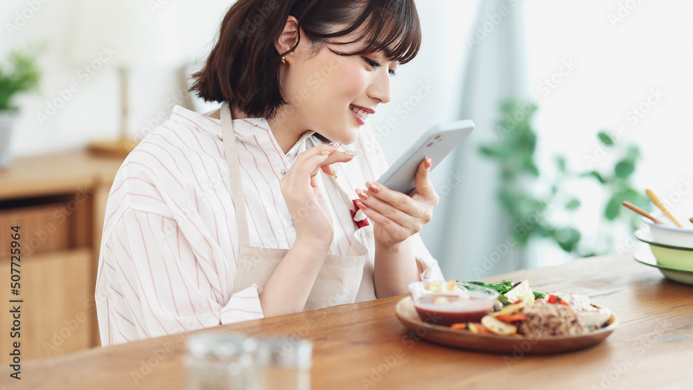 スマホで料理を撮影する若い女性