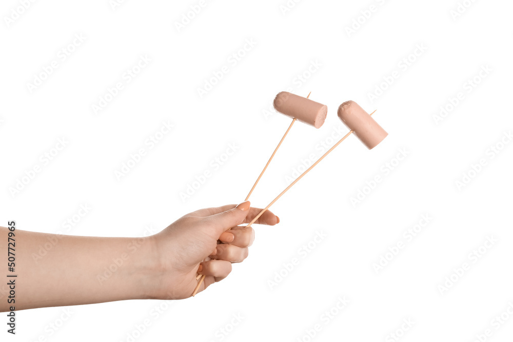 Female hand holding wooden skewers with sausage on white background Female hand holding wooden skewers with sausage on white background
