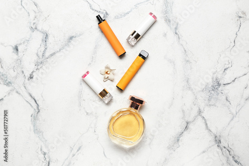 Disposable electronic cigarettes, perfume and vanilla flower on light background
