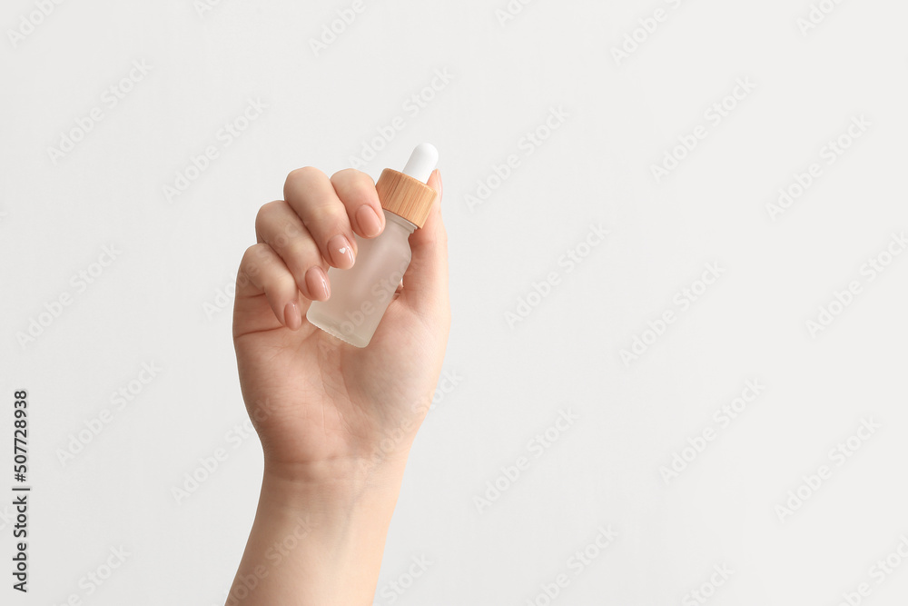Naklejka premium Female hand with bottle of serum on white background, closeup