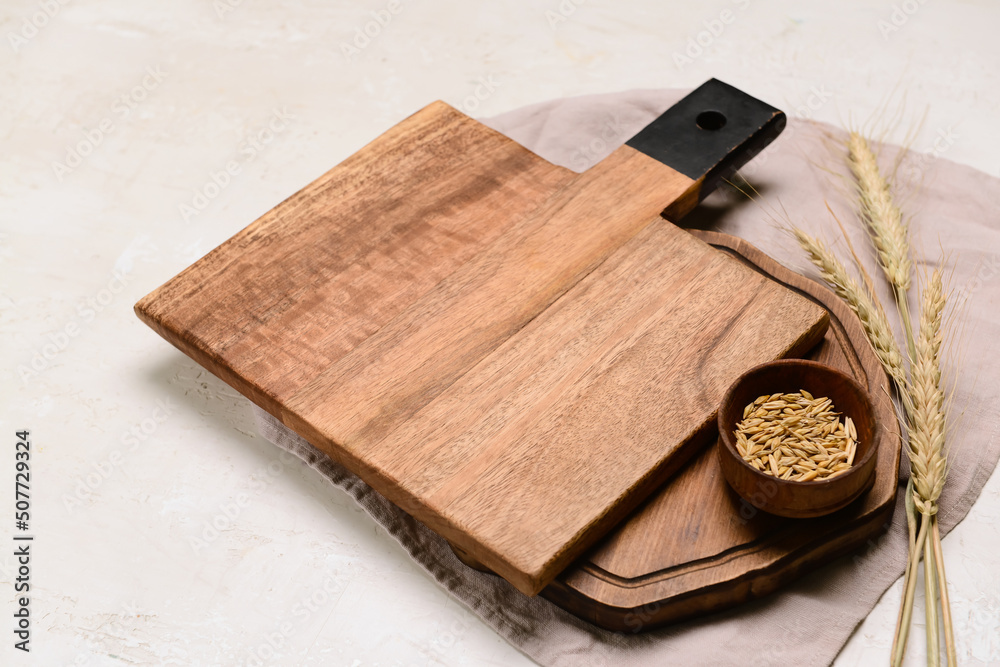 Fototapeta premium Wooden cutting boards and bowl of wheat grains on light background