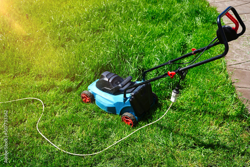 Electric lawnmower machine trimming green grass. Lawn cutting summer time