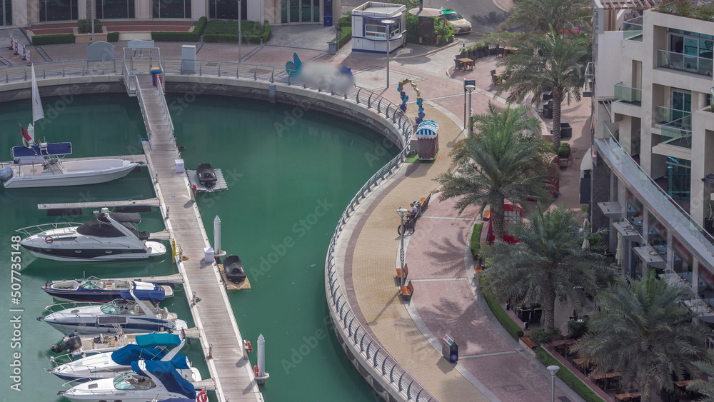 Waterfront promenade with palms in Dubai Marina aerial timelapse.